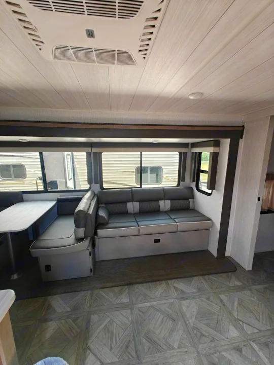 Modern gray rv rental interior: spacious living and dining area with sofa, dinette, and patterned flooring.. Forest River Salem 2024