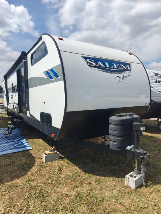 White Salem Platinum travel trailer, an excellent rv rental option, parked on grass under a cloudy sky.. Forest River Salem 2024