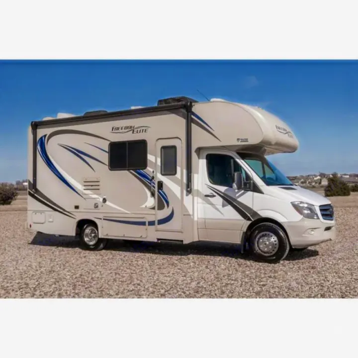 Freedom Elite RV rental on a gravel lot, ready for adventure. Beige Class C motorhome with blue graphics.. Thor Freedom Elite 2018