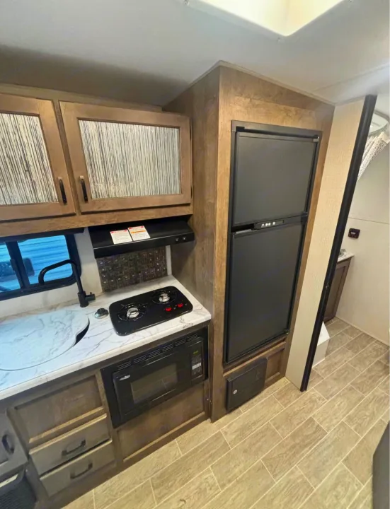 Compact RV rental kitchen with sink, two-burner stove, microwave, and refrigerator for convenient travel.. Sonic Lite 2021