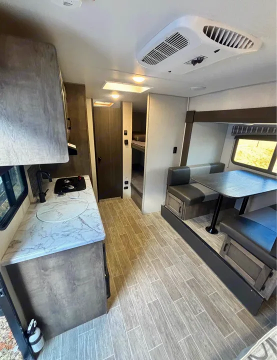 Spacious RV rental interior featuring a modern kitchen, dinette, and private bunk beds. Enjoy comfort on the road!. Sonic Lite 2021