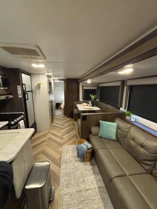 Modern rv rental interior with living area, kitchen, dining booth, and distinctive herringbone flooring.. Forest River Wildwood 2020