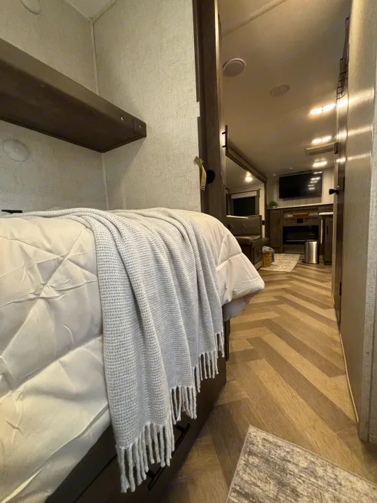 Experience comfort in this modern RV rental! View of a cozy bunk bed area leading to a living space with a TV and fireplace.. Forest River Wildwood 2020