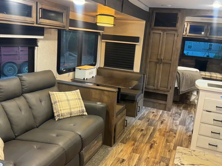 Cozy rv rental interior: dark sofa, dinette, wood-look floor. A comfortable and well-appointed space for your adventures.. Sport Trek Touring Edition 2023