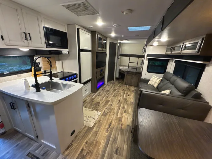 Modern RV rental interior featuring a full kitchen, comfortable living area, and bunk beds for travel and camping.. Sport Trek Touring Edition 2023