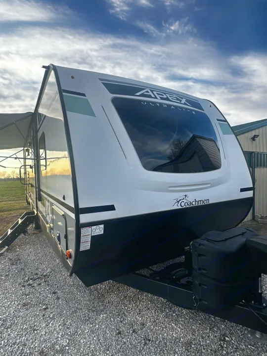 This white Coachmen Apex Ultralite travel trailer, perfect for an rv rental, is parked on gravel under a cloudy sky.. Coachmen Apex 2021