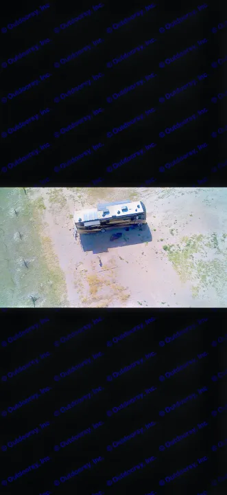 Aerial shot of an rv rental with solar panels, parked on gravel next to a marshy shoreline, casting a long shadow.. Fleetwood Bounder 2013