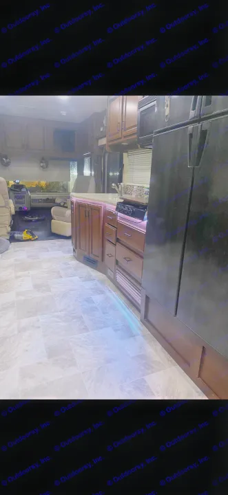 RV rental interior showcases a well-appointed kitchen with warm wood cabinets, purple accent lighting, and light tile floor.. Fleetwood Bounder 2013