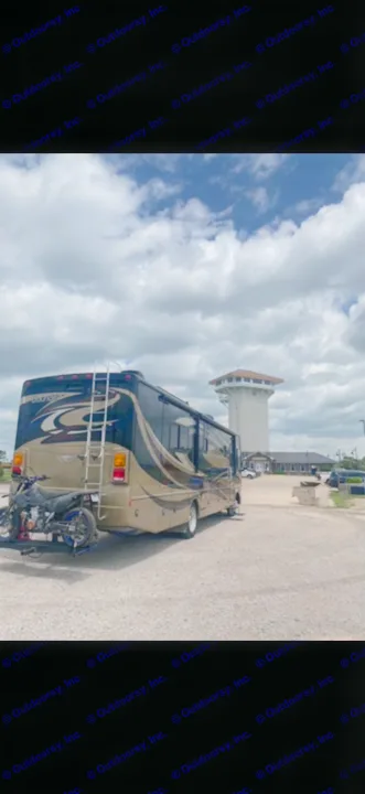 Luxurious rv rental with motorcycle mount parked by a scenic tower under a cloudy sky, ready for adventure.. Fleetwood Bounder 2013