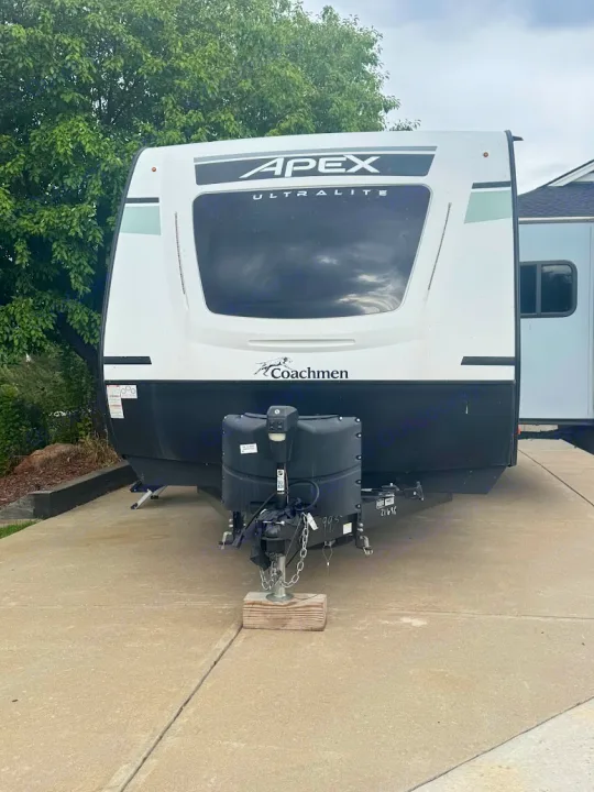 Front of a white and black Coachmen Apex Ultralite travel trailer, equipped for an rv rental adventure. It's parked on a concrete surface.. Coachmen Apex 2021