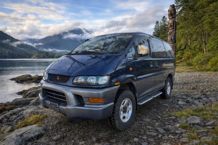 Explore wilderness with this off-road Mitsubishi Delica, ideal for rv rental, by a scenic lake, mountains & totem pole.. Mitsubishi Delica 2000