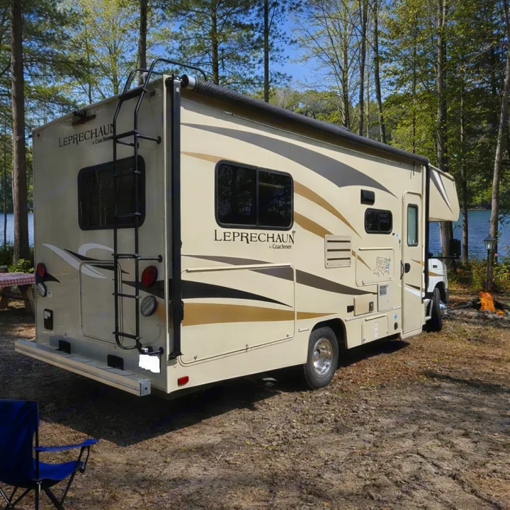 This Coachmen Leprechaun Class C RV rental is parked at a serene lakeside campsite, ideal for travel and camping adventures.. Coachmen Leprechaun 2018