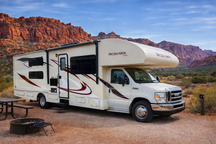 RV rental: Class C Jayco Redhawk parked at a scenic desert campsite with red mountains, picnic table, and fire pit.. Jayco Redhawk 2016