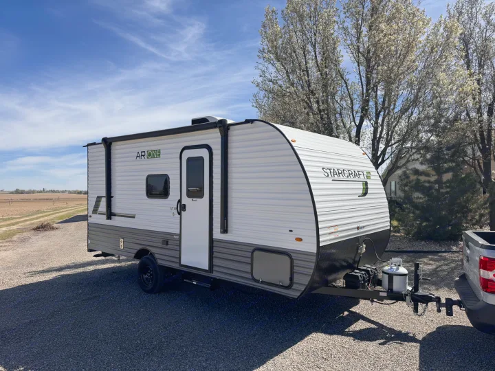 A white Starcraft AR ONE travel trailer, an ideal rv rental, is hitched to a truck, ready for outdoor adventures.. Starcraft Autumn Ridge 2026