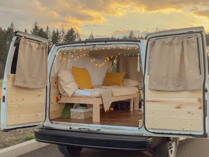 Explore in comfort with this charming van conversion! An ideal rv rental featuring a cozy bed, string lights, and wooden interior.. Chevrolet Astro 2005