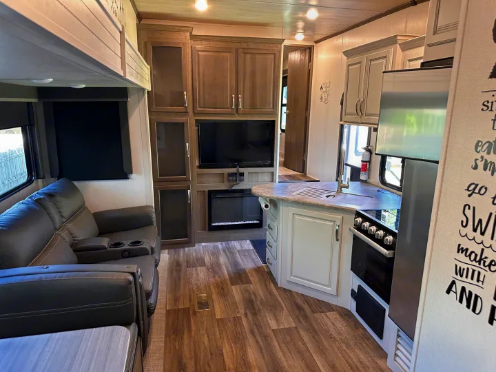 Modern RV rental interior: spacious living area with recliners, entertainment center, and full kitchen.. Keystone RV Cougar 2022