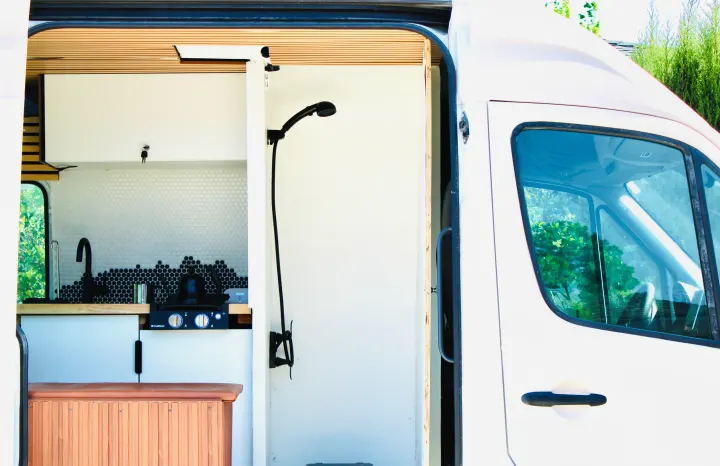 This RV rental features a modern campervan kitchen with a sink, stovetop, and a compact shower, ideal for mobile living.. Mercedes-Benz Sprinter 2008