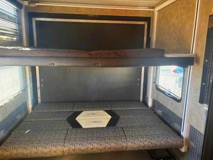 This rv rental features a versatile lower bench-style bed/couch with an upper bunk bed, flanked by windows with blinds.. Keystone RV Fuzion Toy Hauler 2009