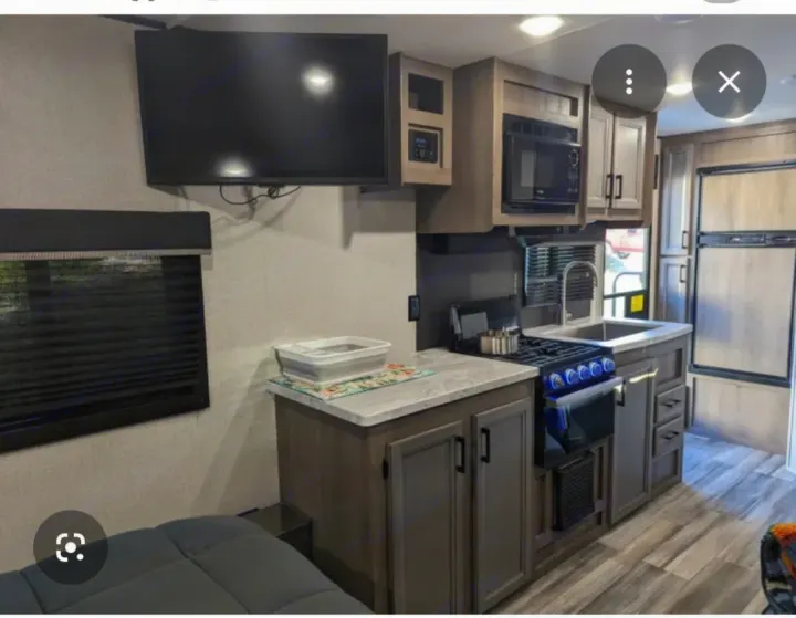 Inside an RV rental: full kitchen with oven/stove, microwave, sink, fridge, and wall-mounted TV.. Starcraft Autumn Ridge 2024