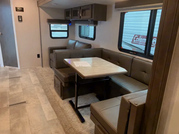 RV rental interior featuring a cozy dinette with U-shaped seating, overhead cabinets, and windows.. Forest River Rockwood Ultra Lite 2021