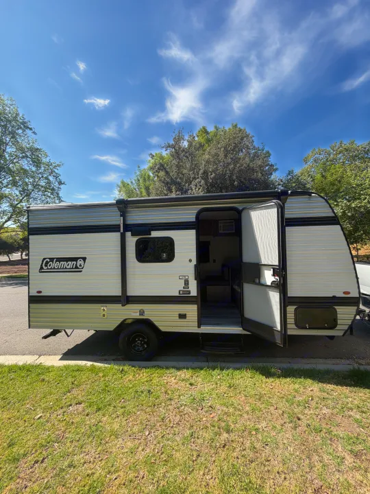 This Coleman travel trailer RV rental, with its door open and interior visible, is parked on a sunny day, ready for adventure.. Coleman 17B 2026