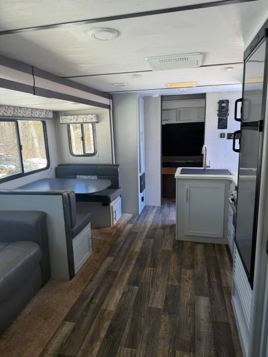 Bright, modern rv rental interior: dinette, kitchen, and comfy living area with wood-look floors & grey accents.. Keystone RV Bullet Ultra Lite 2019