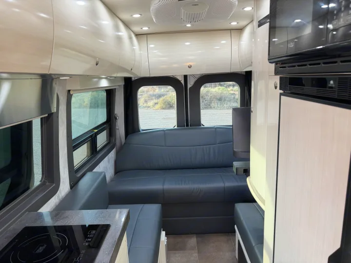 Modern rv rental interior: spacious living area with gray sofa, full kitchen, microwave, and overhead storage.. Pleasure-Way Pleasure-Way Class B 2022