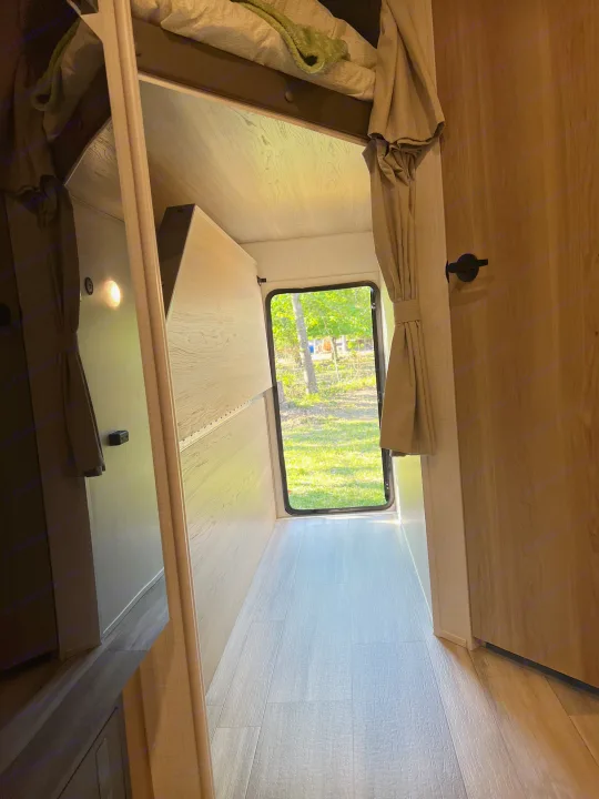 Bright RV rental interior hallway with bunk bed, mirror, and outdoor view through the back window.. Forest River Rockwood Mini Lite 2024