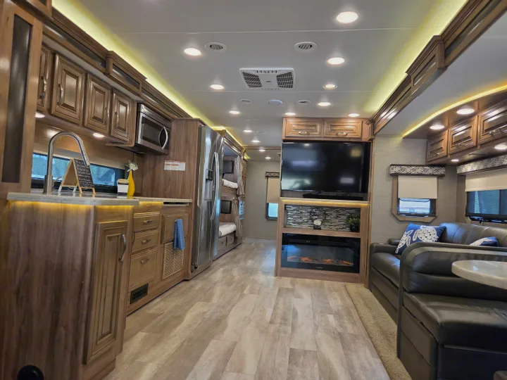 Explore this modern **rv rental** interior: a full kitchen, cozy living area with TV & fireplace, and bunk beds.. Jayco Seneca 2021