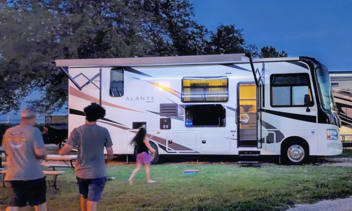 Experience RV rental camping. Two motorhomes, including a lit Jayco Alante, parked at dusk with people walking nearby.. Jayco Alante 2021
