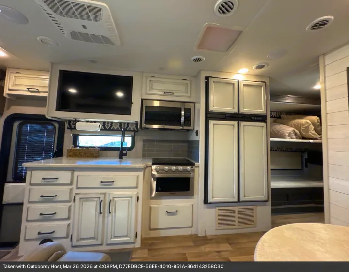 Modern RV rental interior with a bright kitchen, featuring microwave, oven, fridge, and comfortable bunk beds.. Entegra Coach Vision XL 2021