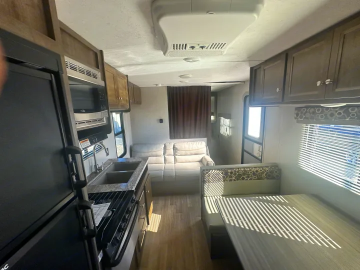 Tour this RV rental's inviting interior: full kitchen, comfortable sofa, and dinette with sunlit blinds.. Keystone RV Coleman 2019