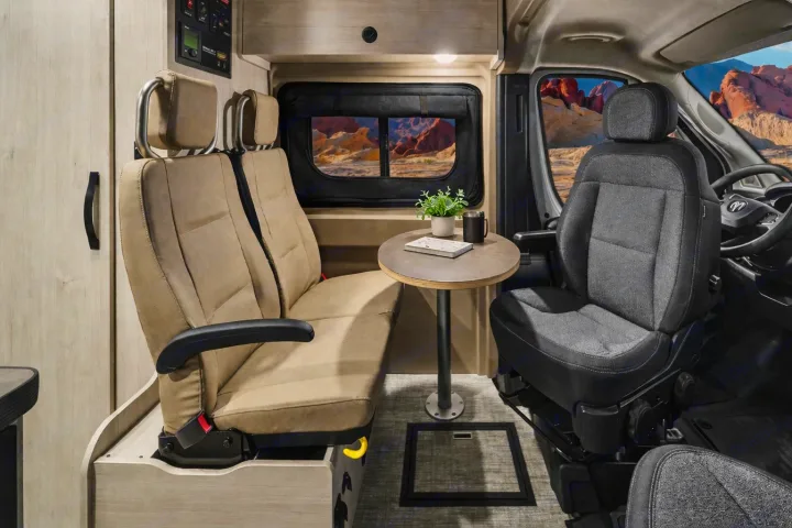 Modern RV rental interior: comfortable swivel seats, dining table, and a scenic desert window view for your road trip adventures.. Winnebago Solis 2026