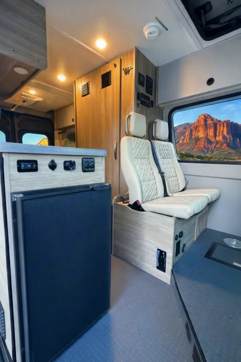 Modern **rv rental** interior with comfy seating, fridge, and a breathtaking desert mountain view from the window.. Winnebago Solis 2026
