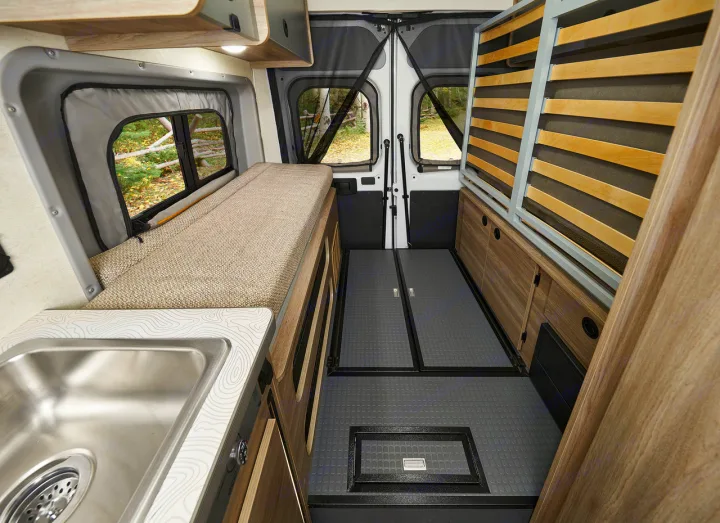 Explore this modular camper van interior, perfect for your next RV rental. Features a sink, bed, storage, and scenic views.. Winnebago Solis 2025