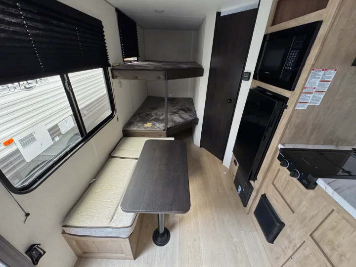 RV rental interior with a cozy dinette, bunk beds, microwave, and stove, ideal for family adventures.. Forest River WOLF PUP 17LP 2026