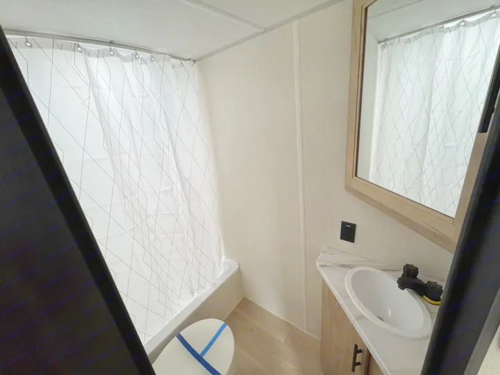 Inside an RV rental bathroom: compact shower/tub with curtain, toilet, and vanity with sink & mirror. Functional and tidy.. Forest River WOLF PUP 17LP 2026