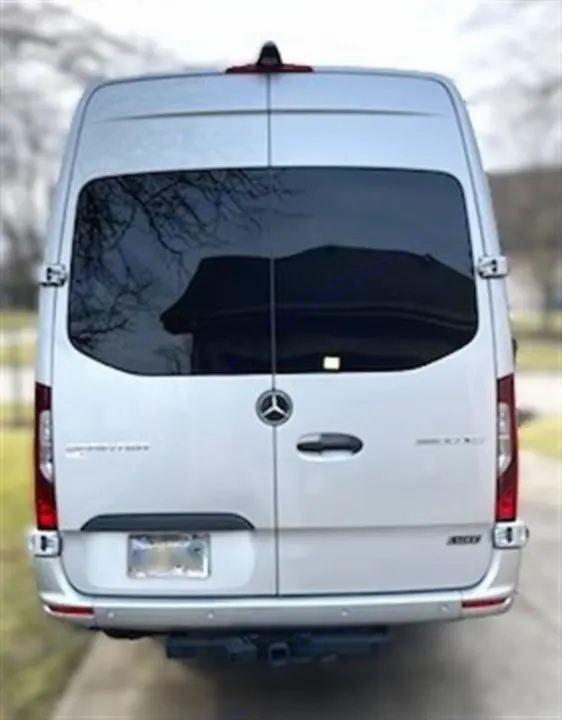 Rear view of a silver Mercedes-Benz Sprinter van, perfect for an RV rental adventure. Tinted windows & hitch.. Mercedes 3500XD 2023