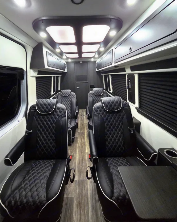 Luxury RV rental interior: plush black leather seats, bright overhead lights, and storage compartments create a comfortable travel space.. Mercedes 3500XD 2023