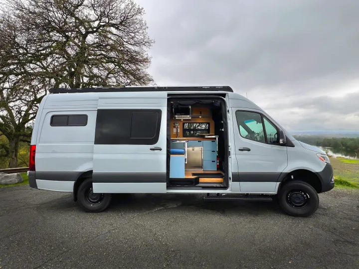 Explore in style with this light grey rv rental camper van, showcasing its open side door and modern interior with a kitchen.. Mercedes-Benz Sprinter 2024