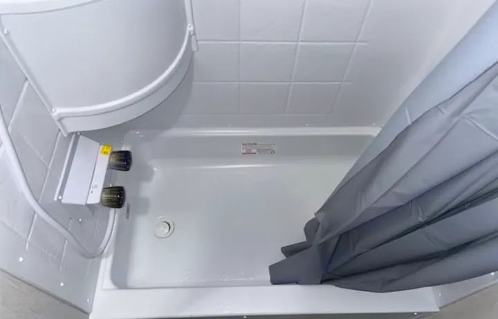 This RV rental offers a compact, clean white shower with visible controls and a practical gray shower curtain.. Forest River Cherokee Wolf Pup 2024