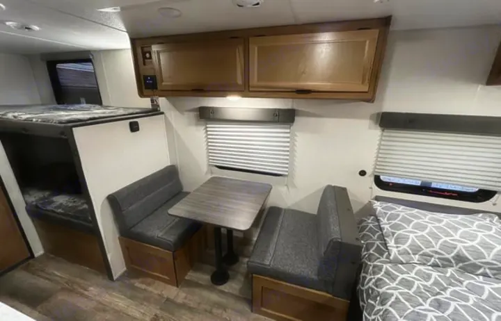 RV rental interior featuring bunk beds, a dinette, main bed, and overhead storage cabinets for compact living.. Forest River Cherokee Wolf Pup 2024