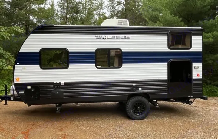Explore in this stylish Wolf Pup RV rental! A compact travel trailer with white/blue stripes, black trim, and rugged tires.. Forest River Cherokee Wolf Pup 2024