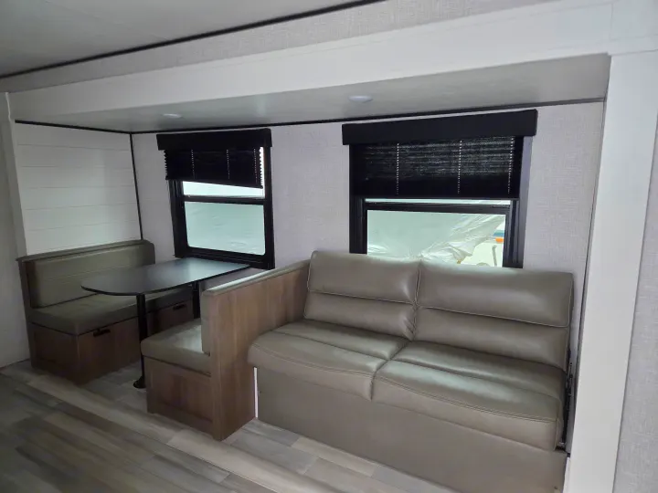 RV rental: Interior view of a dinette area with table, a sofa, and windows with dark pleated blinds.. Open Range Conventional 26BHS Travel Trailer 2025
