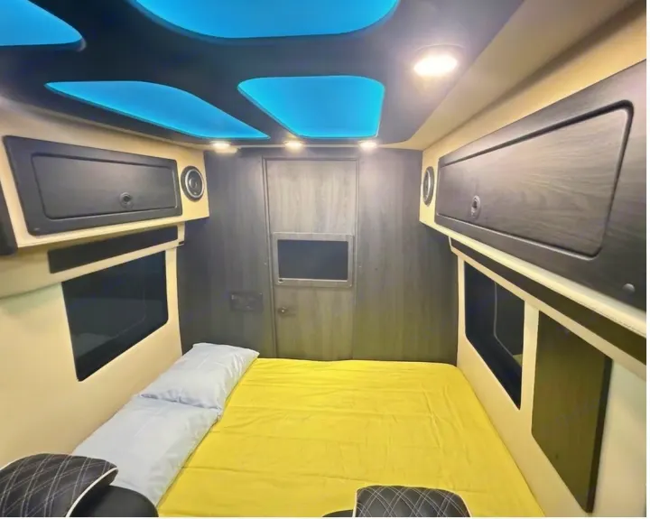 Modern RV rental bedroom: Features a comfortable yellow bed, sleek storage, and blue ambient lighting. Ideal for mobile adventures.. OGV Luxury Coach V-Cruise 2026