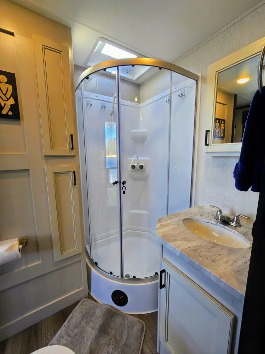 RV rental bathroom: a bright, modern space with a curved glass shower, vanity, mirror, and cabinet storage.. Highland Ridge RV Mesa Ridge 2021