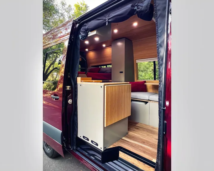 Explore this modern camper van rv rental interior: wood-paneled walls, compact kitchen, and inviting bed for road trips.. Mercedes-Benz Sprinter 2025