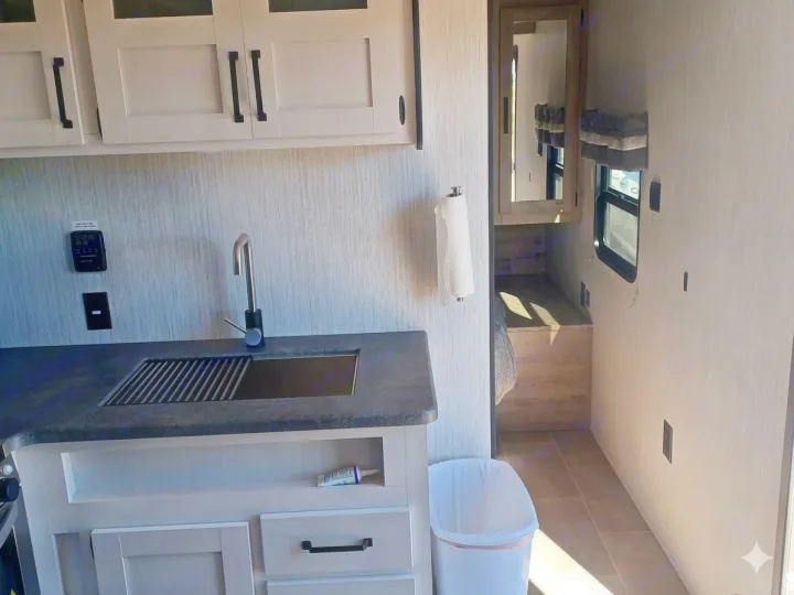 RV rental: functional kitchen with modern cabinets, sink, and paper towels, leading to a compact living area.. Forest River Palomino Puma XLE Lite 2021