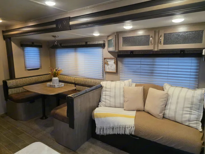 Inside a modern RV rental: a comfortable dinette, plush sofa with throw pillows, and ample overhead storage.. Palomino puma 2020