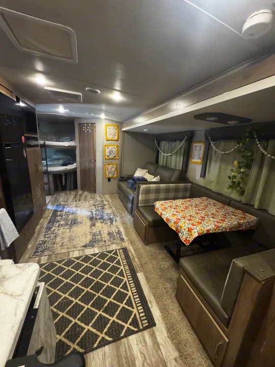 Spacious rv rental interior: living area, dining booth, bunk beds. A comfortable home on wheels for family travel.. Grand Design Imagine 2022